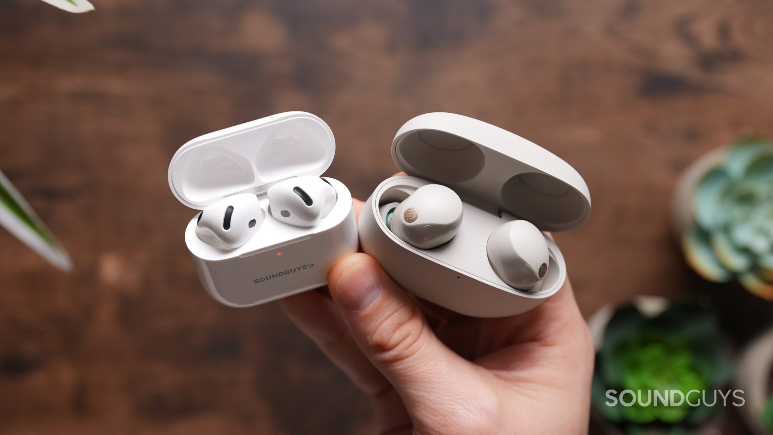 a hand holding the airpods 4 and sony xm5 earbuds a hand holding the airpods 4 and sony xm5 earbuds