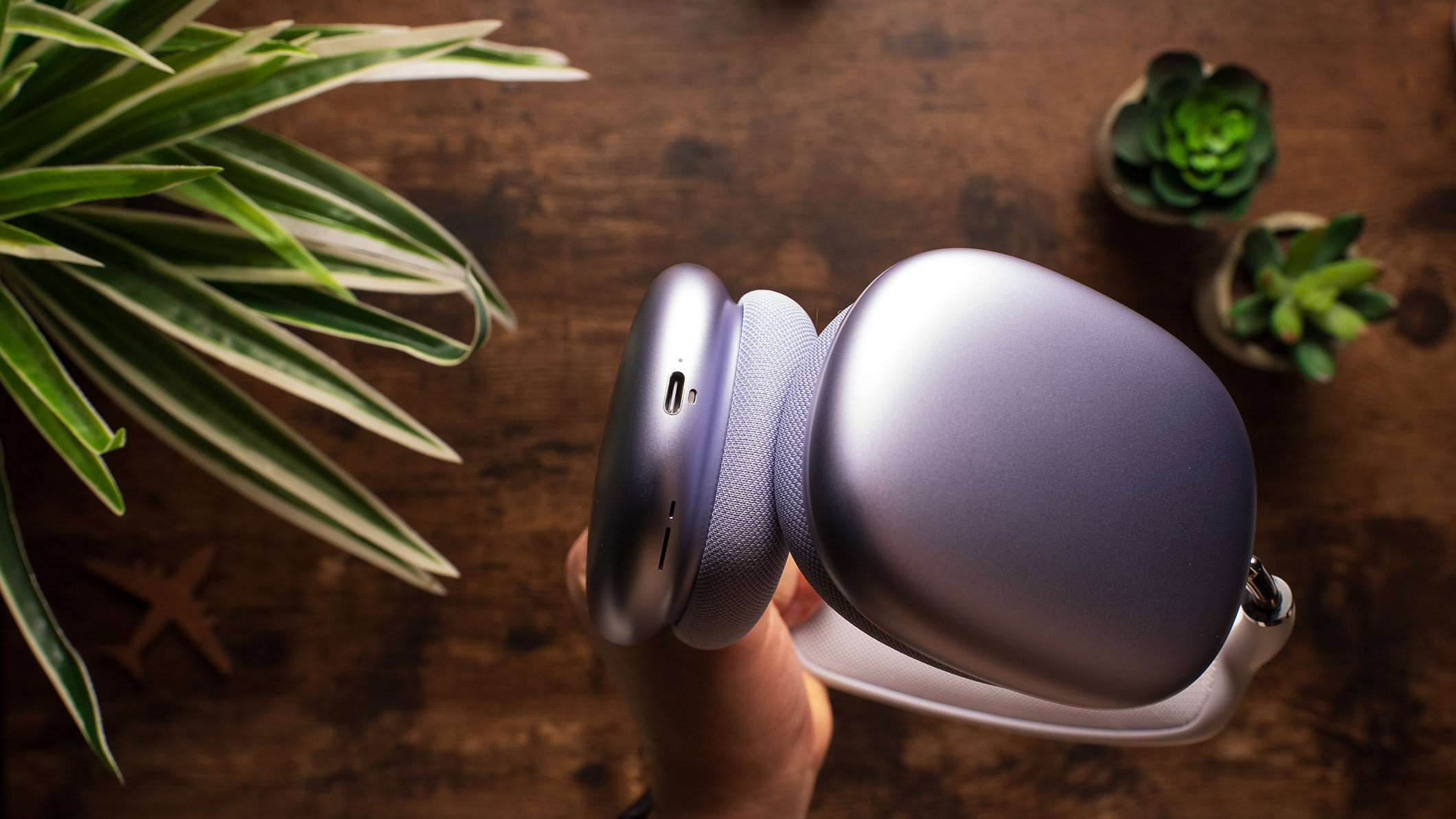 Airpods Max USB C Lilac A hand holds the AirPods Max showing the USB-C charging port.