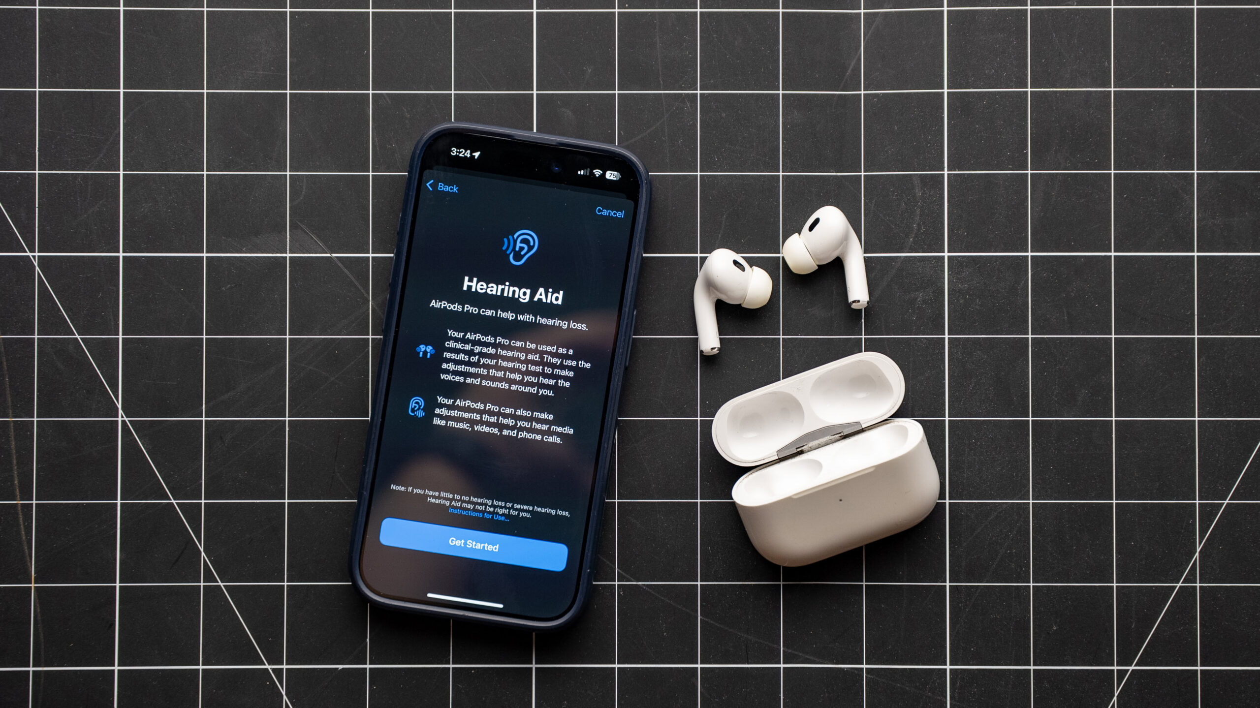 airpods pro 2 hearing aid setup guide settings page AirPods Pro 2 on the table next to iPhone showing Hearing Aid features setup screen.