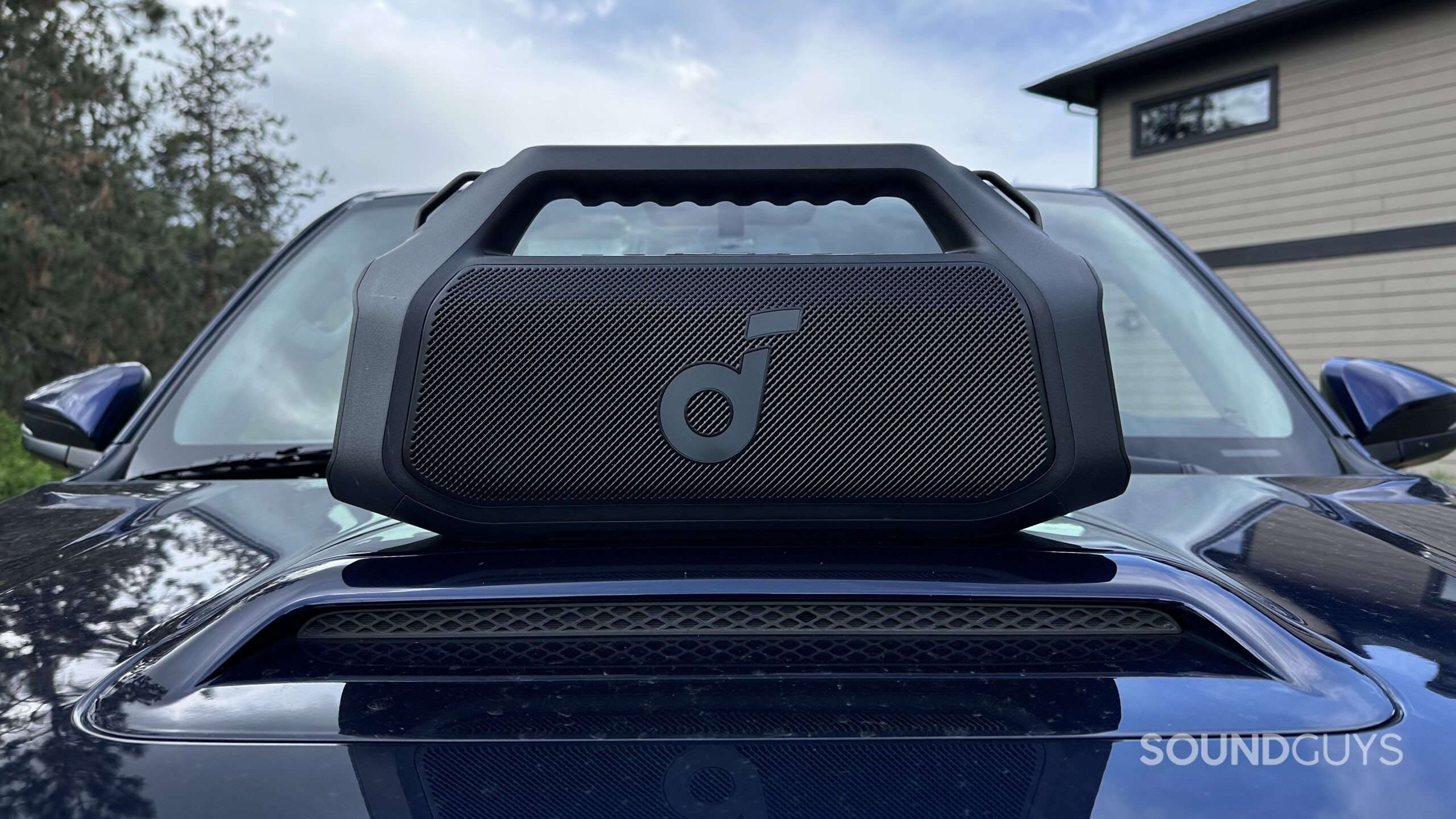 Anker Soundcore Boom 2 Plus 1 An Anker Soundcore Boom 2 Plus is placed on top of an automobile hood, facing the camera.
