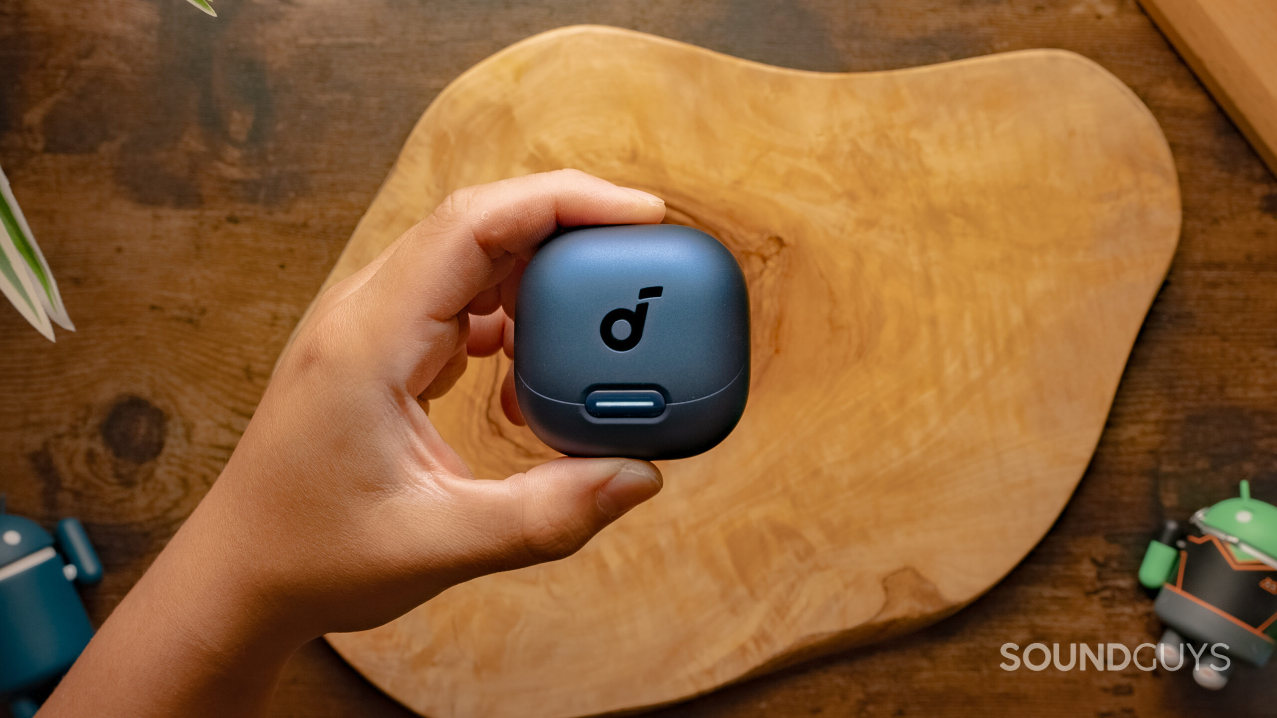 Anker-Soundcore-Liberty-4NC-Featured-Image-#3 A hand holds the Anker Soundcore Liberty 4 above a wood surface.