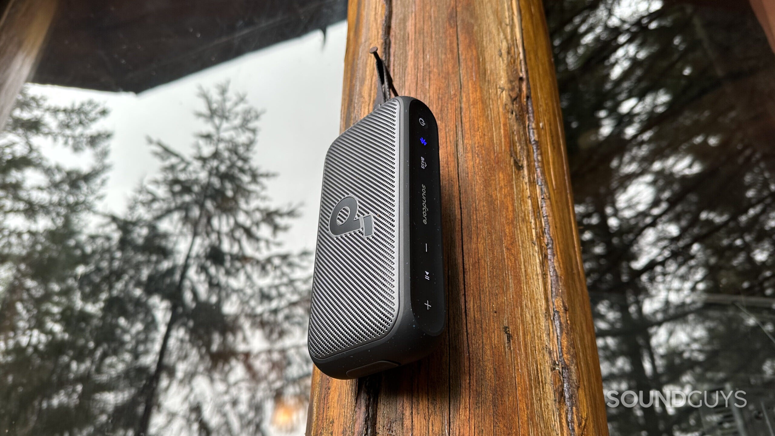 Anker Soundcore Motion 300 hanging A Soundcore Motion 300 speaker hanging from a nail outside a cabin.