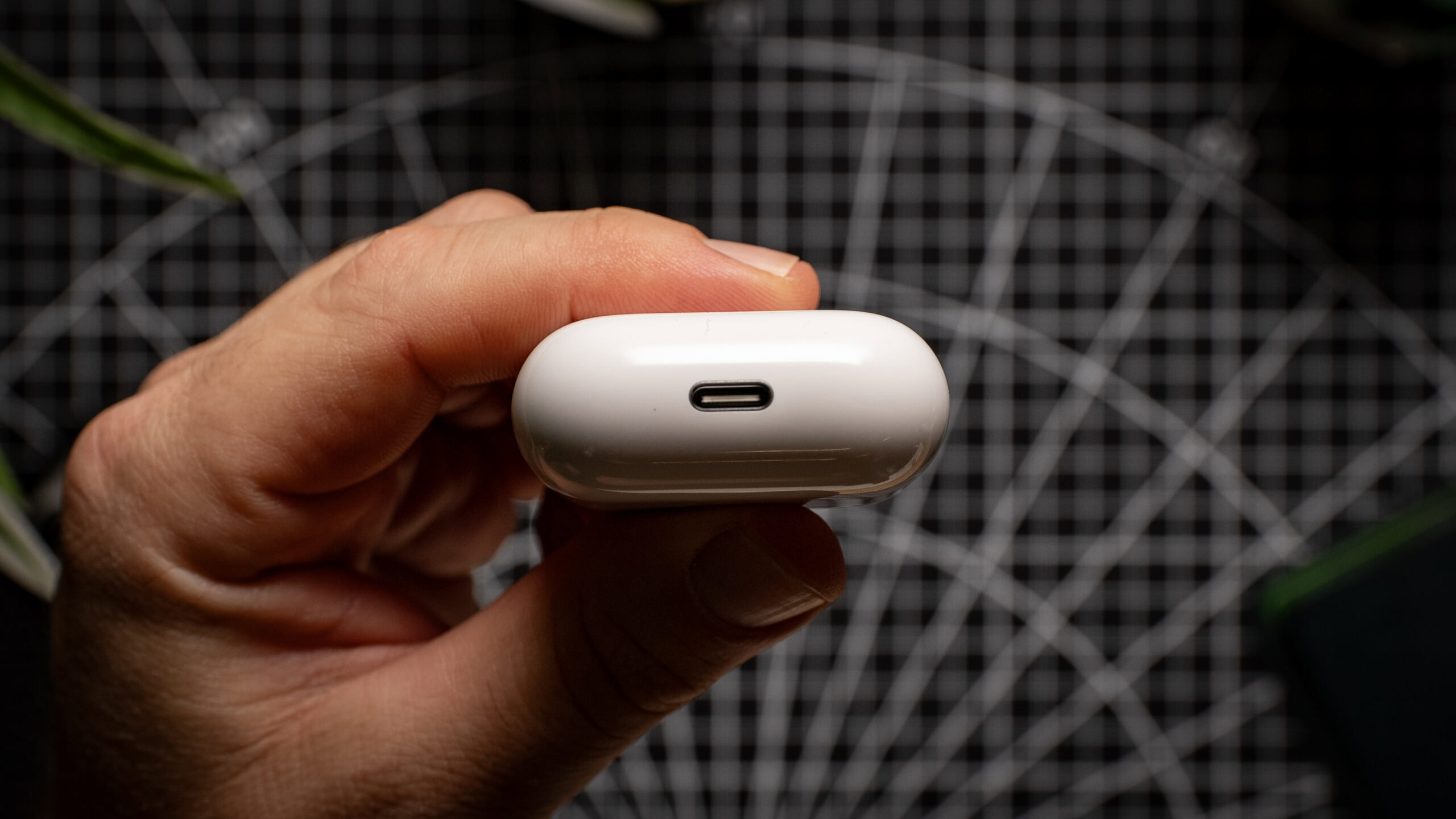 Apple AirPods 4 charging case USB-C port A hand holds the AirPods 4 charging case, showing the USB-C port.