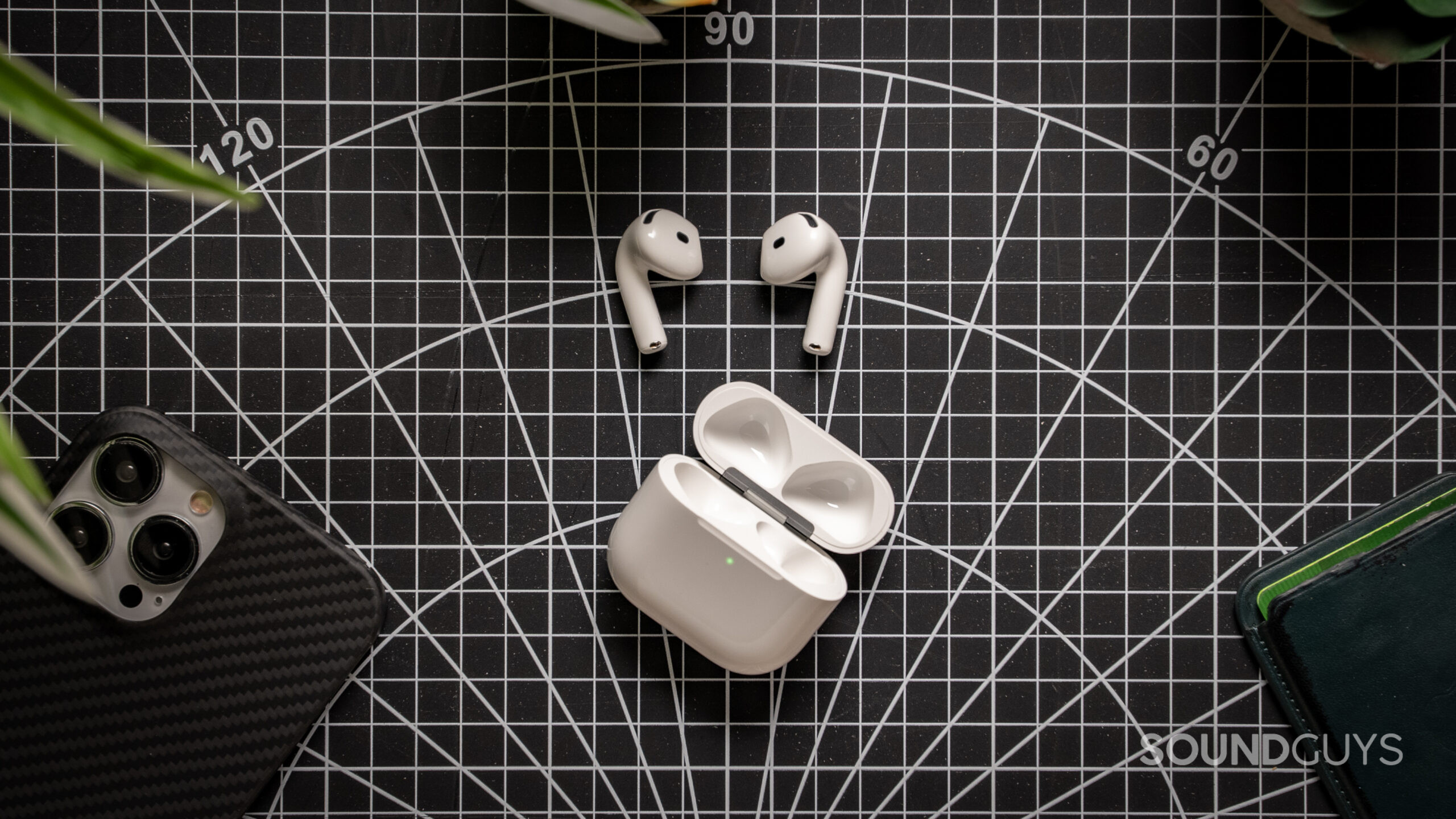 Apple AirPods 4 on table out of case AirPods 4 earbuds next to their case on a table.