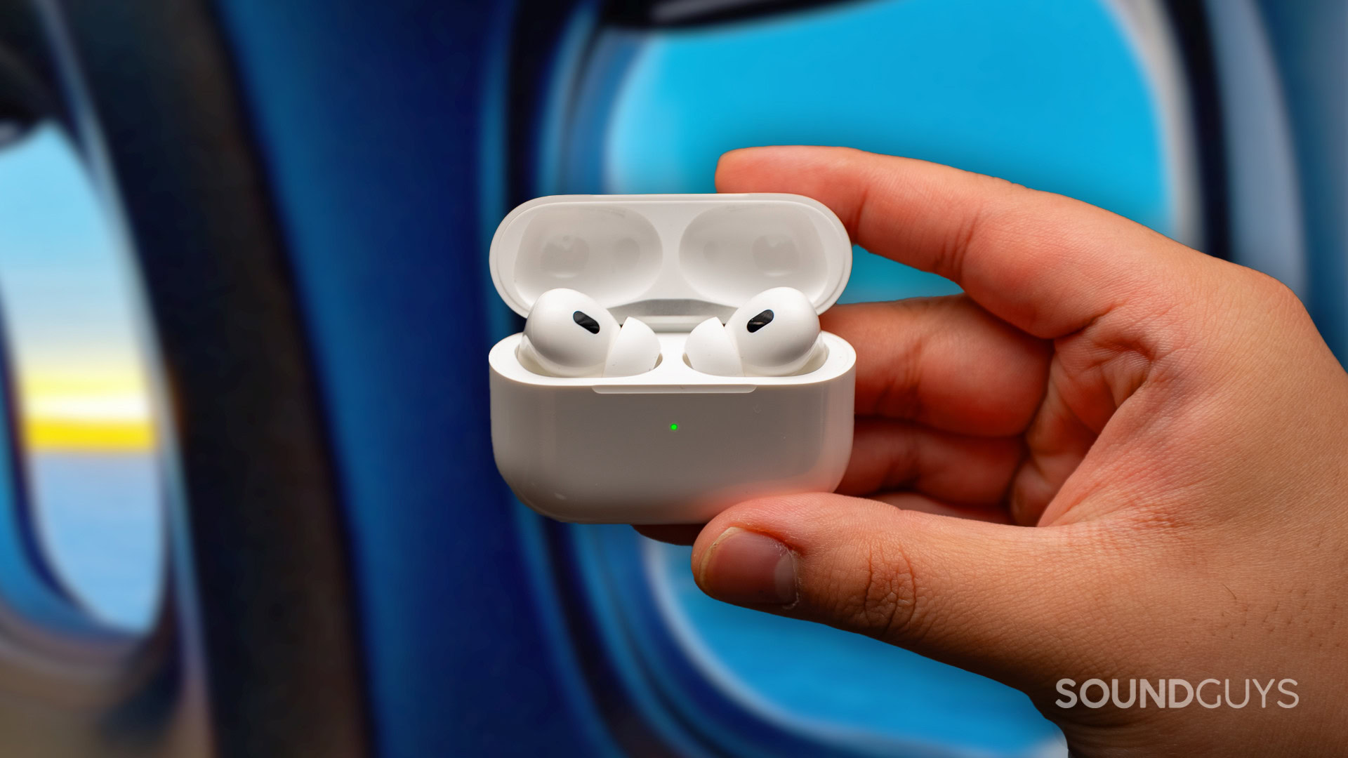 apple airpods pro 2 in front of airplane window The Apple AirPods Pro 2 in hand in front of airplane cabin windows.