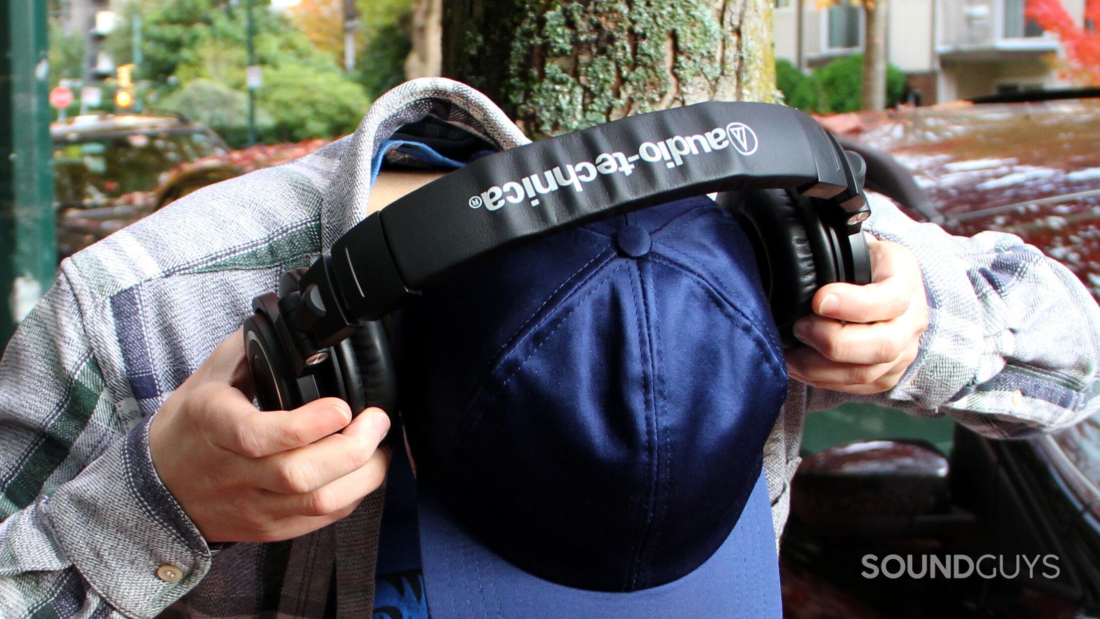 audio-technica-ath-m50xbt2-on-head A man puts on the Audio-Technica ATH-M50xBT2, showing the top of the headphones.
