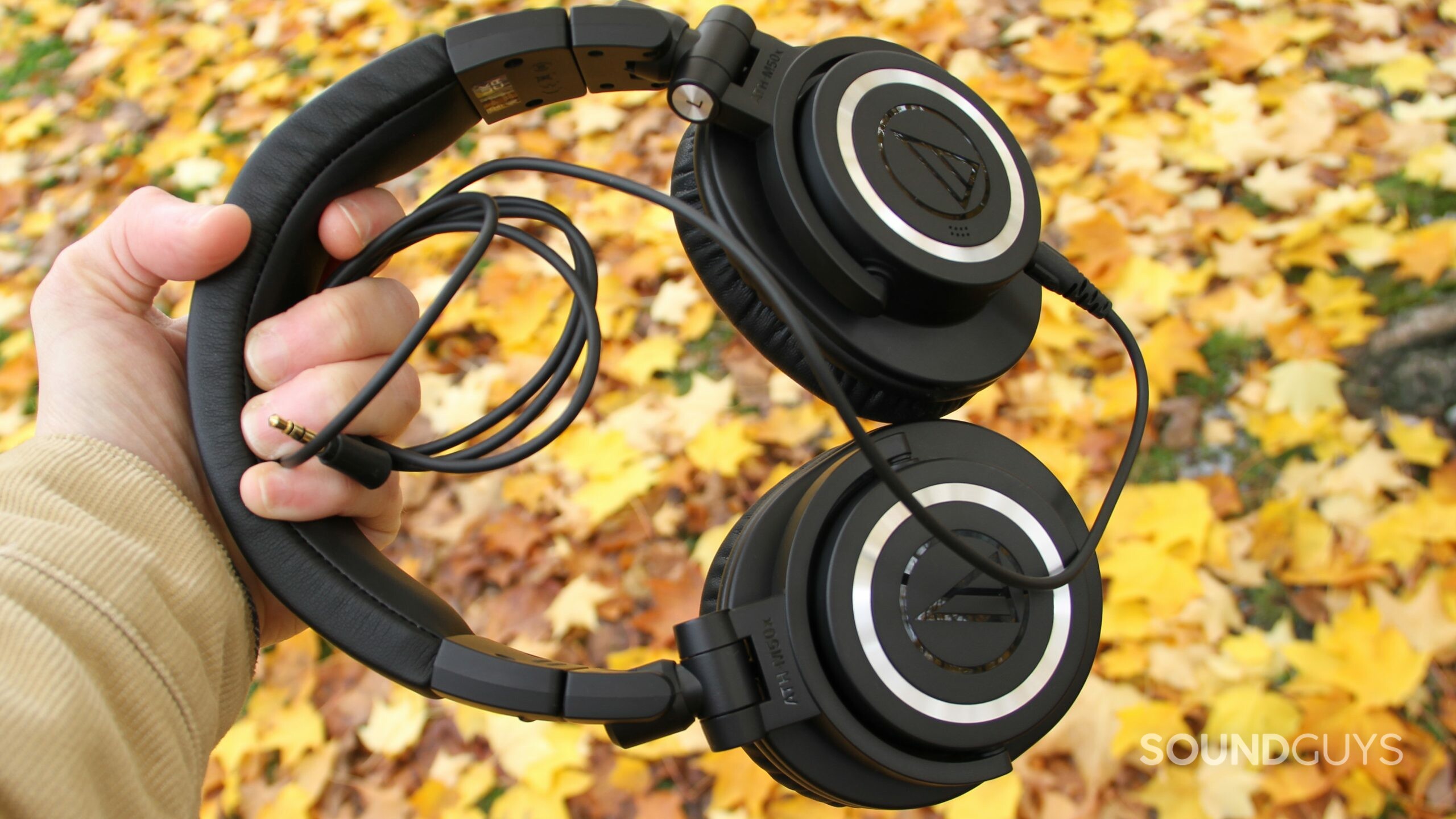 audio-technica-ath-m50xbt2-wired Audio-Technica ATH-M50xBT2 with headphone cable plugged in, held in a hand.