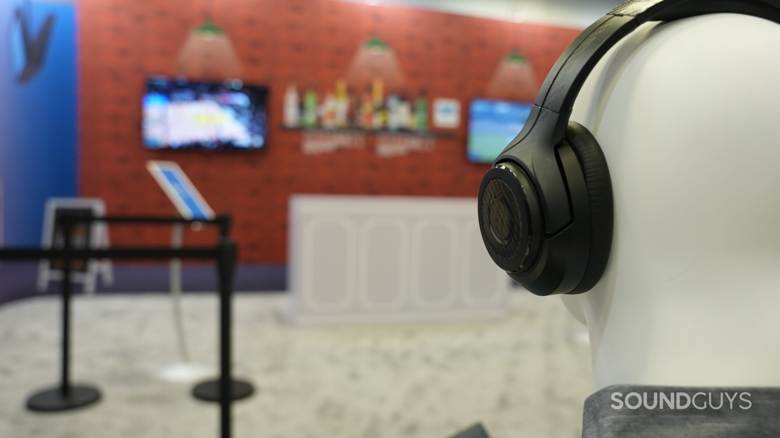 Auracast broadcast at bar Testing head wearing headphones facing towards multiple TVs.