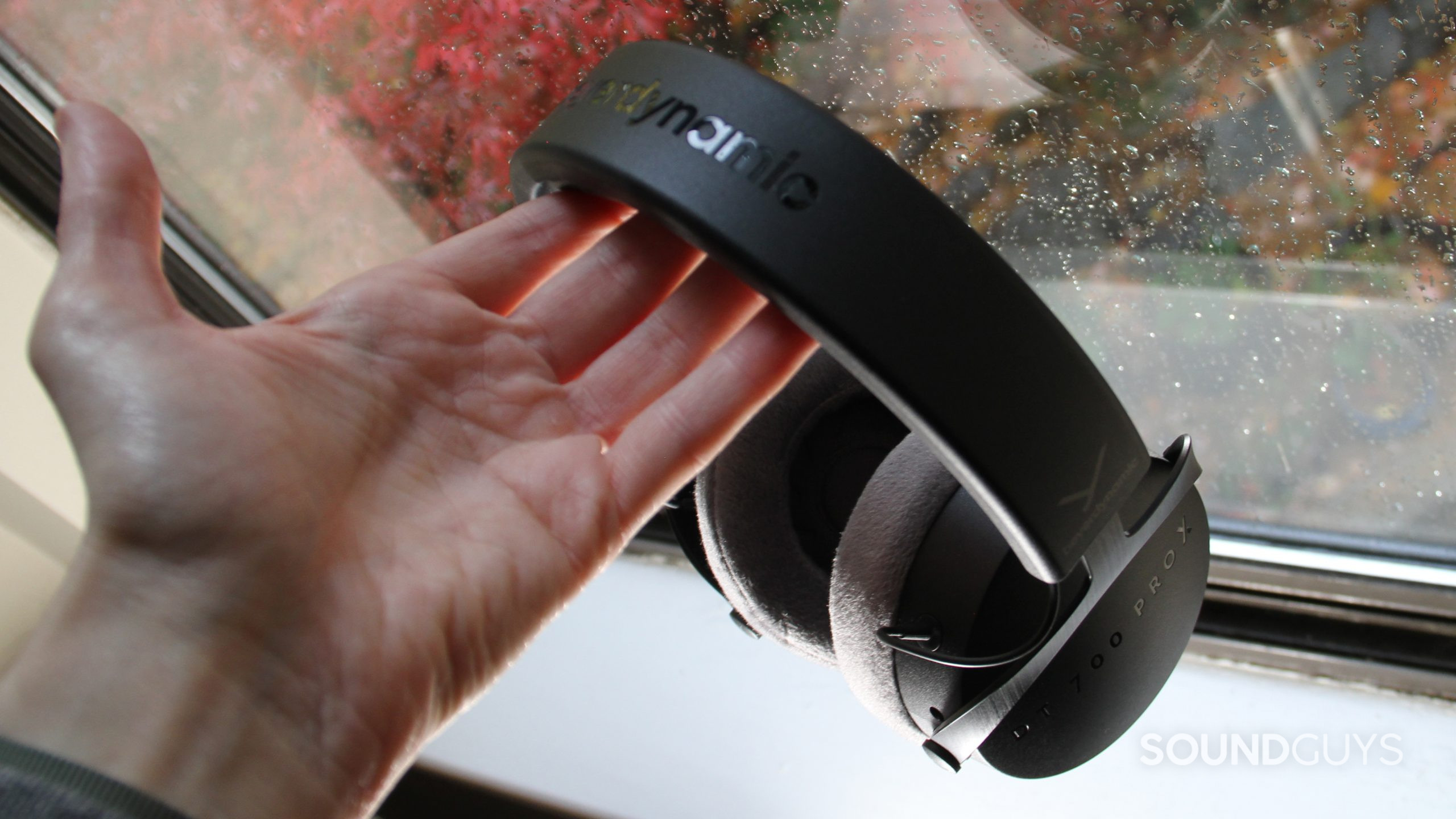 beyerdynamic-dt-700-pro-x-in-hand A man's hand holds the Beyerdynamic DT 700 Pro X by a window.