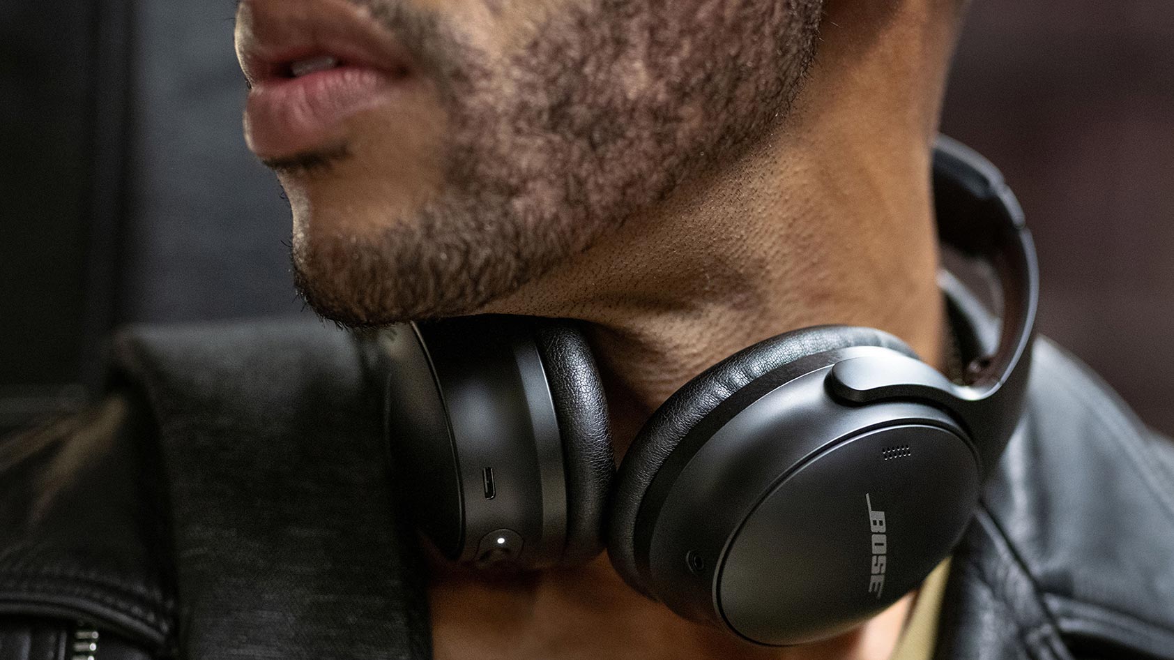 Bose QuietComfort 45 lifestyle man wears A man wears the Bose QuietComfort 45 noise canceling headphones around his neck.