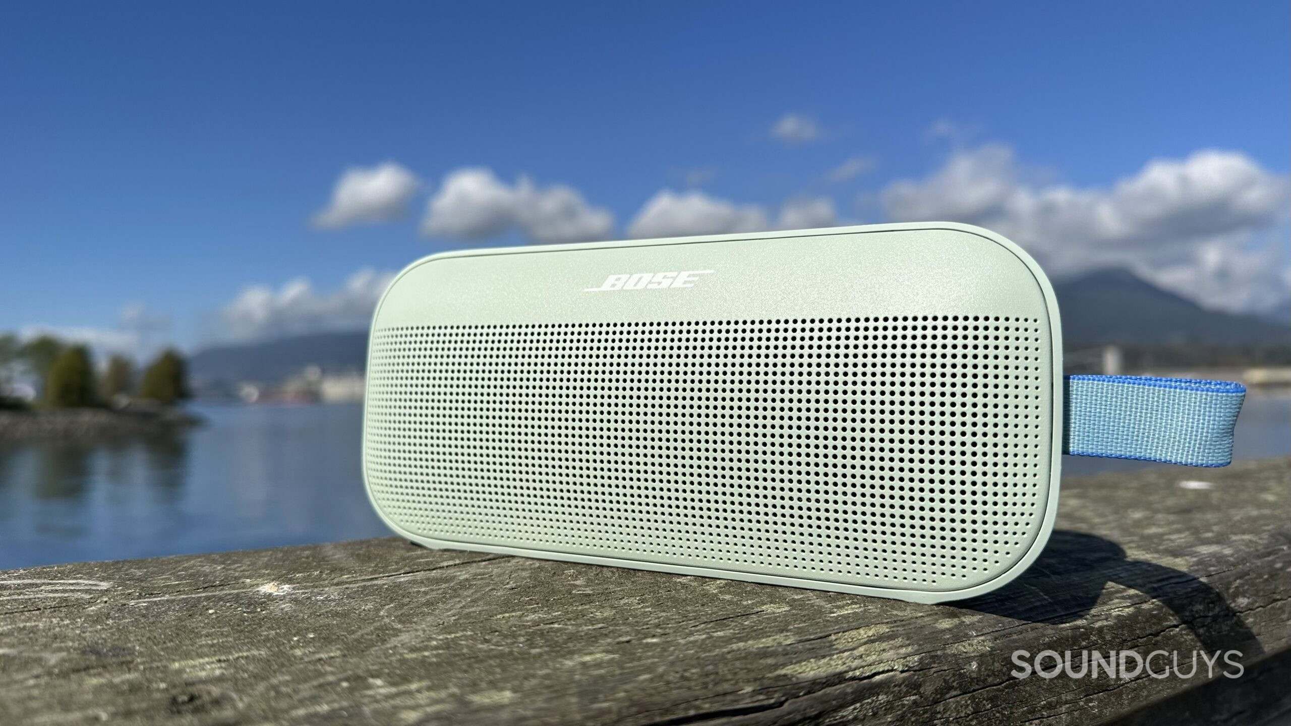 Bose SoundLink 2nd Gen_10 A Bose SoundLink Flex 2nd Gen on a pier with water and mountains in the background.