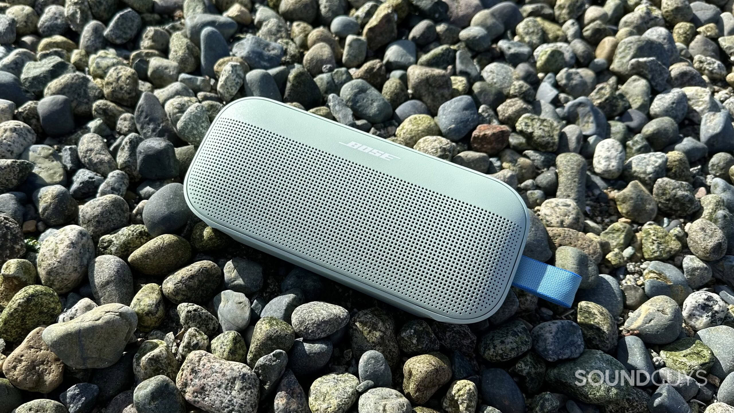 Bose SoundLink 2nd Gen_9 Photo of a Bose SoundLink Flex 2nd Gen resting on some rocks at the beach.