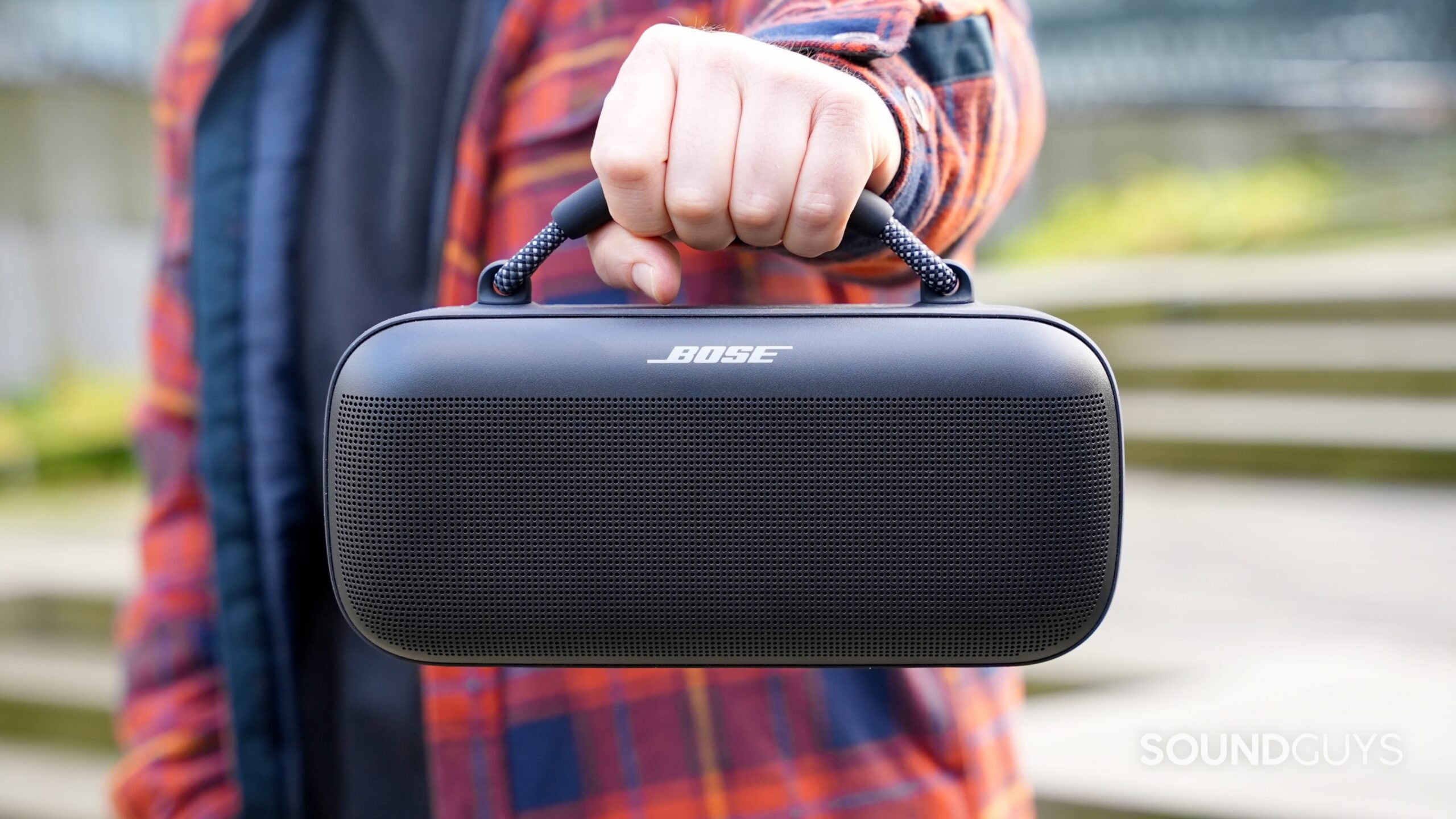 Bose SoundLink Max_13 A hand holds the Bose SoundLink Max speaker in an outdoor setting.
