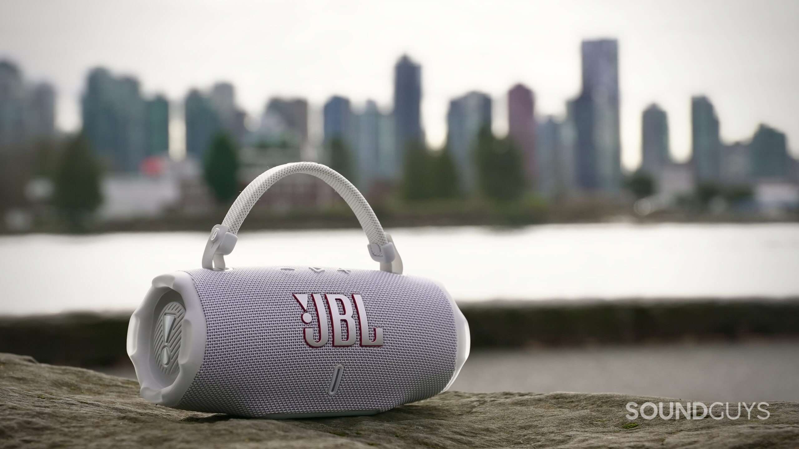 Charge 6 - 1 A JBL Charge 6 speaker resting on a rock with the city in the back ground.