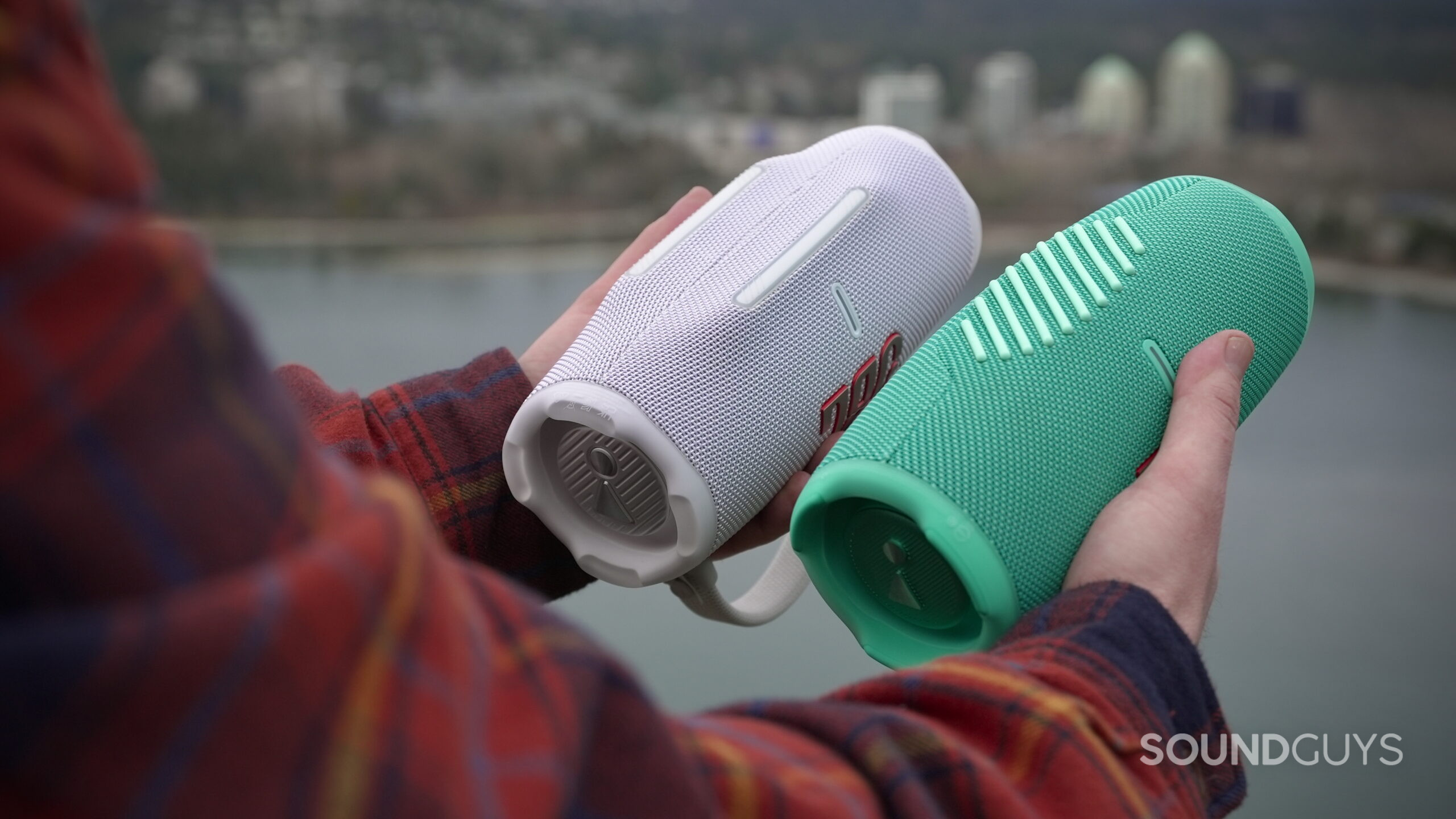 Charge 6 - 10 A man holds a JBL Charge 6 in his left hand and a JBL Charge 5 in his right, showing their undersides.