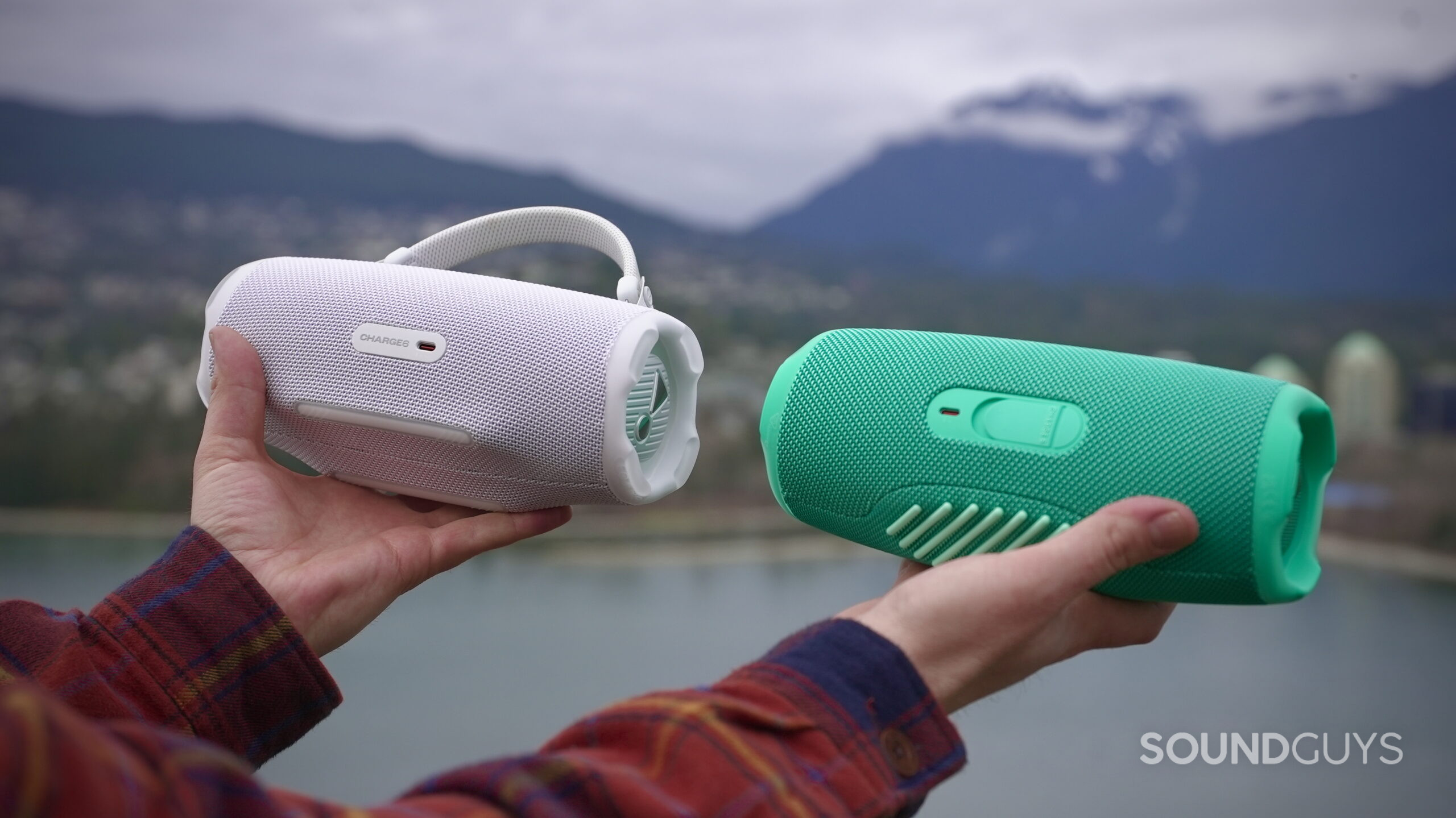 Charge 6 - 11 A man holds a JBL Charge 6 in his left hand, and a JBL Charge 5 in his right, showing their rear charge ports.