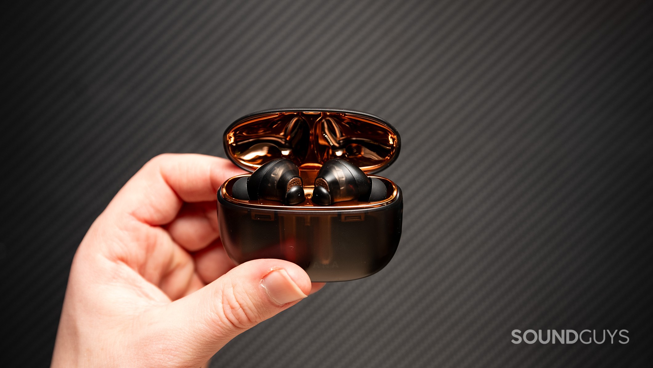 Creative Aurvana Ace 2 held in hand Creative Aurvana Ace 2 earbuds in charging case held above a black table.