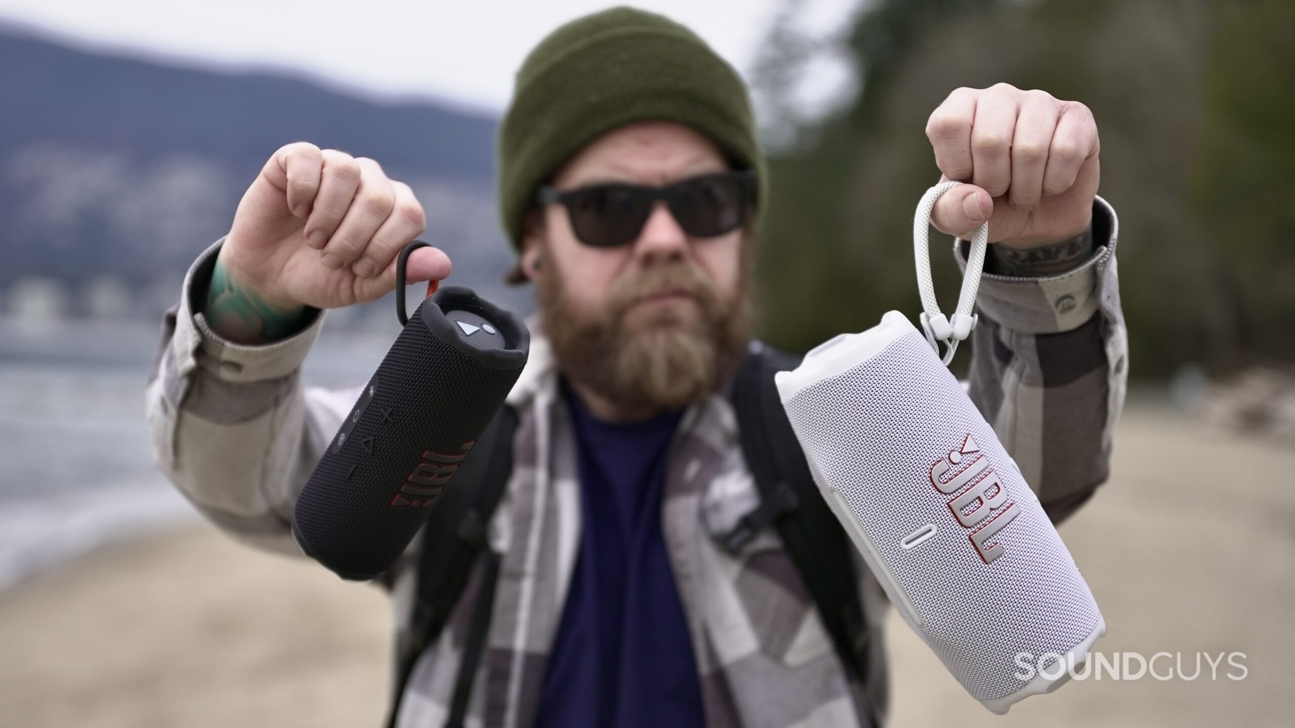 DF785879-343B-427B-9161-87FE8900DB05_1_201_a a man holding the jbl charge 6 and flip 7 speakers