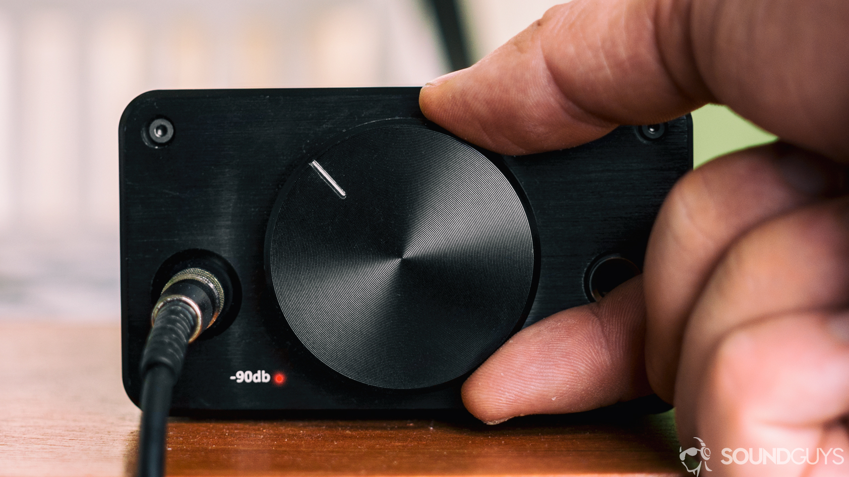 do-you-need-an-amp-hero A photo of a hand turning up the knob of a headphone amplifier