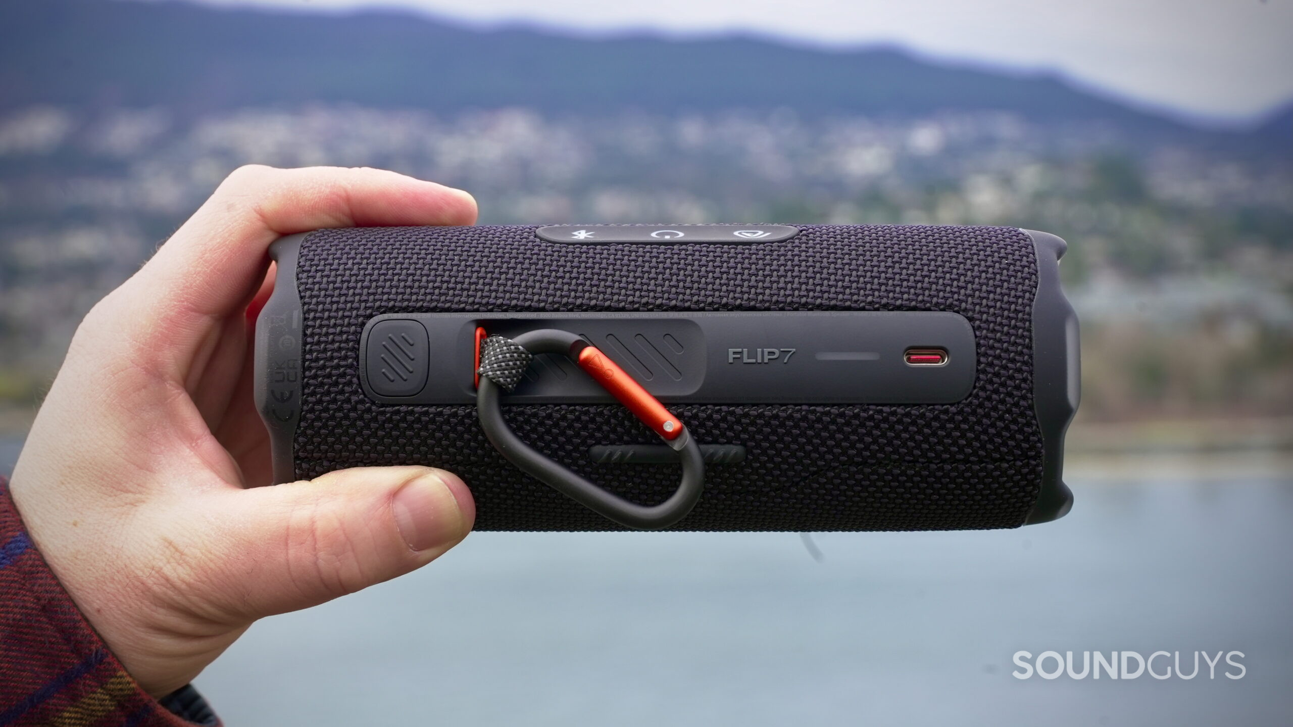 Flip 7 - 6 A hand holds a JBL Flip 7 showing its rear control panel.