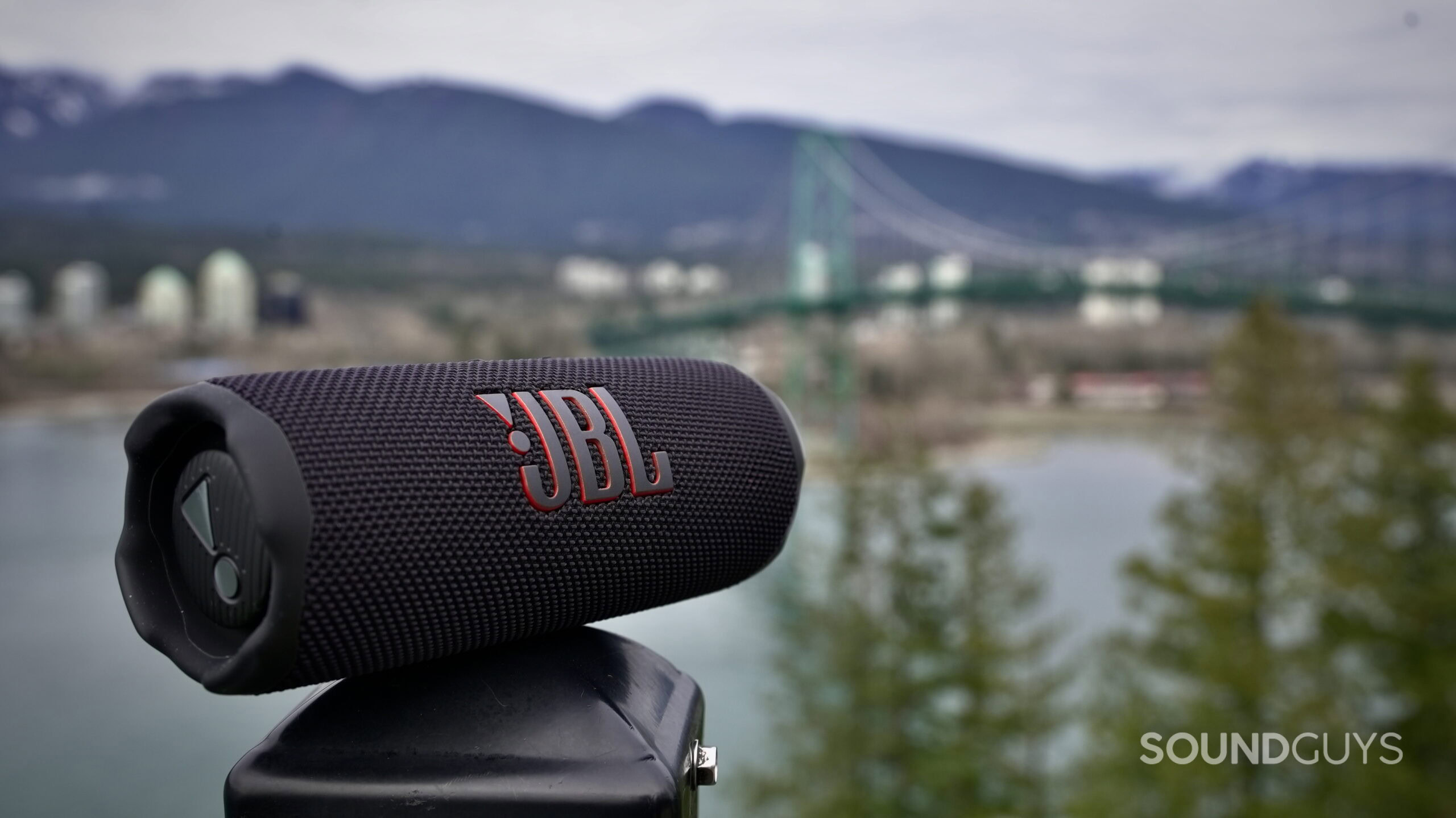 Flip 7 extra hero_2 - 1 A JBL Flip 7 resting on a railing with nature in the back ground.