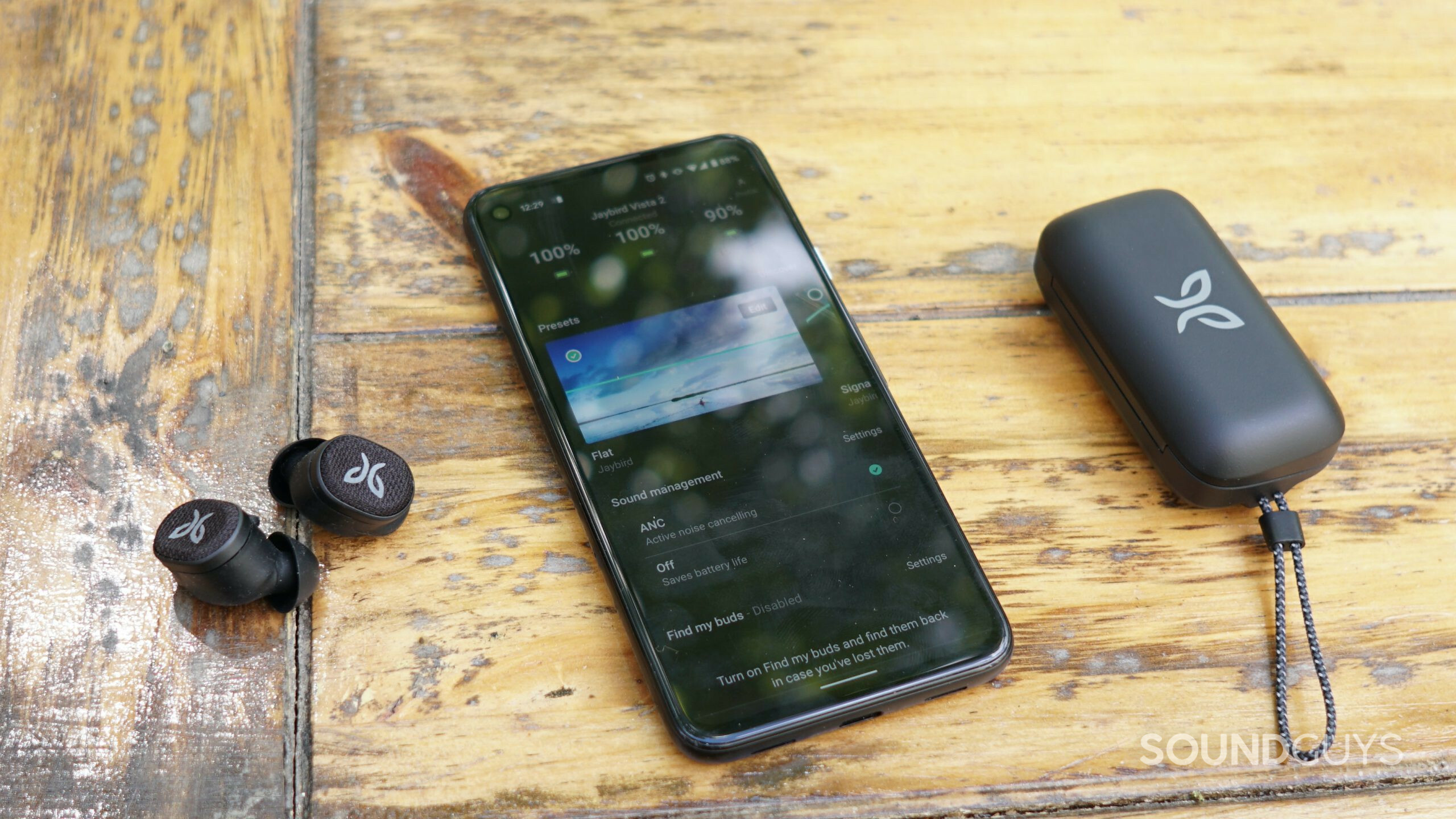 Jaybird-Vista-2-app-shot Jaybird Vista 2 earbuds and case on table next to phone with app open.