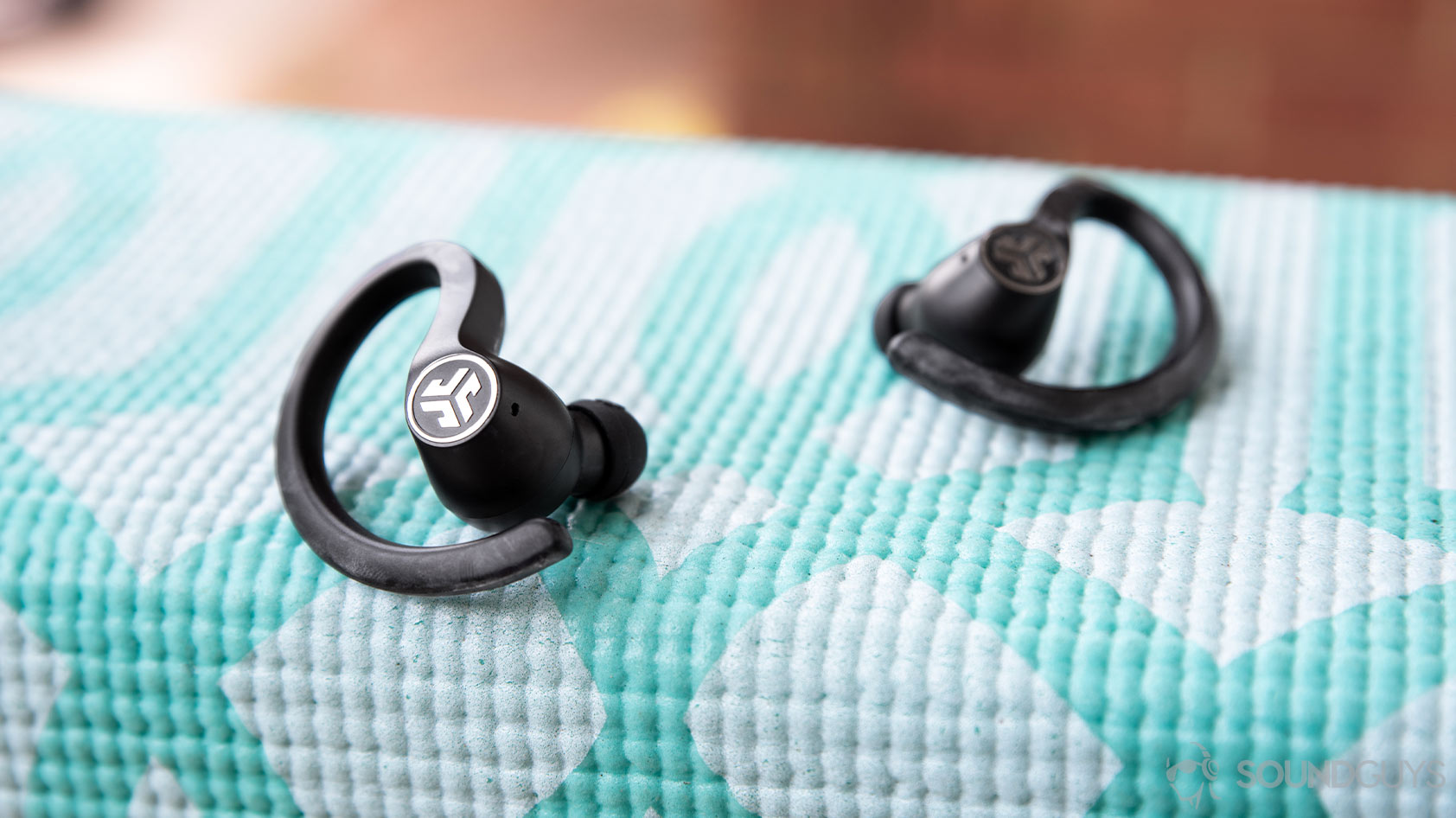 JLab JBuds Air Sport-4_earbuds ear hook close The earbuds resting on a teal yoga mat.