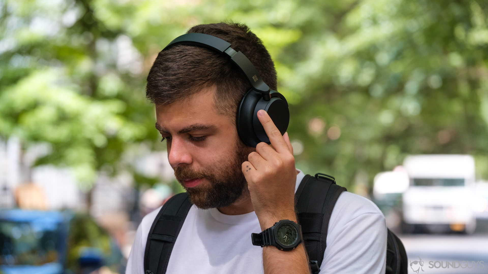 Microsoft Surface Headphones 2 noise canceling control A picture of a man rotating the noise canceling ring on the Microsoft Surface Headphones 2 in front of trees