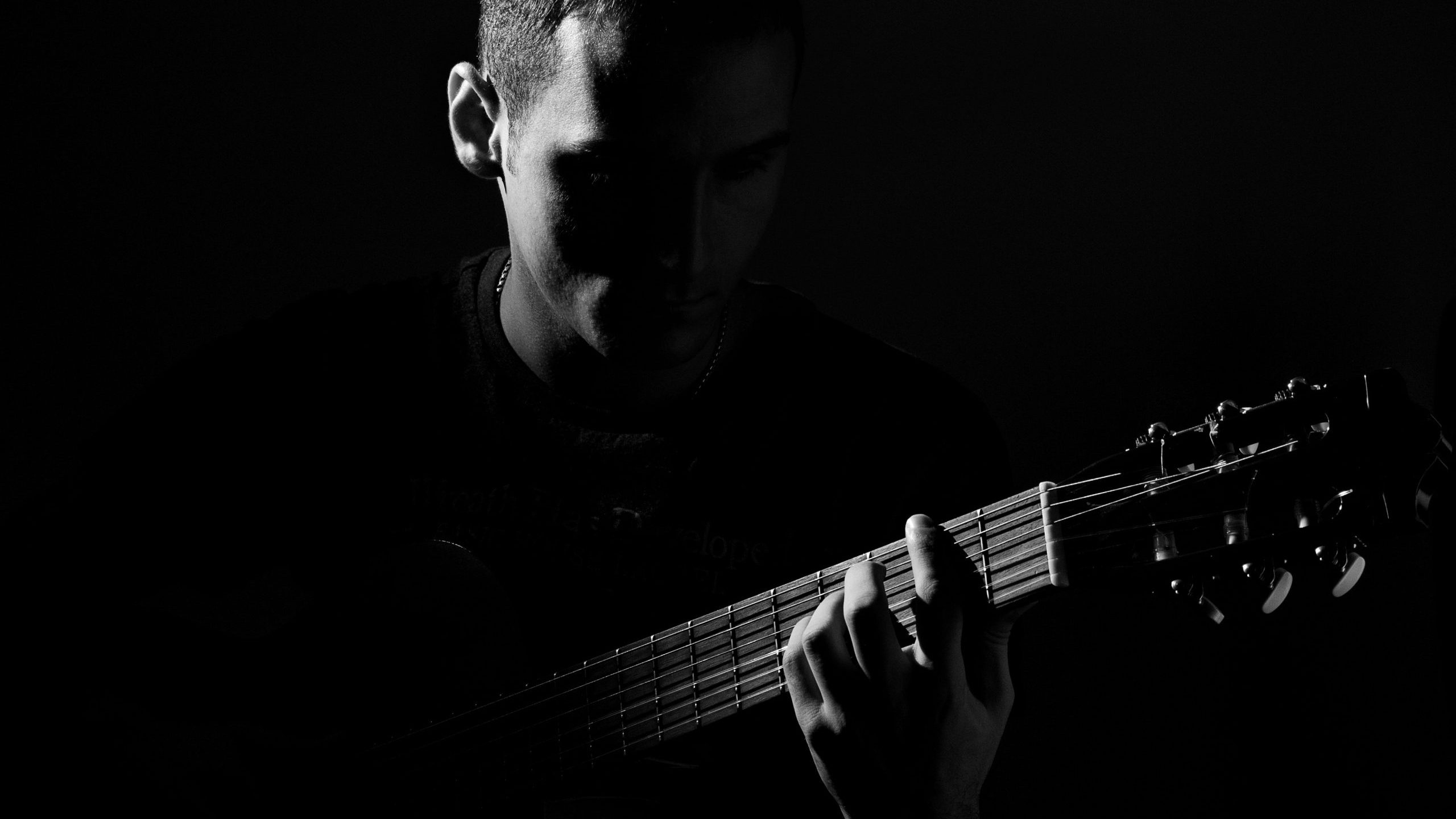 pexels-pixabay-210766 A man plays guitar; this is a darkly lit grayscale image.