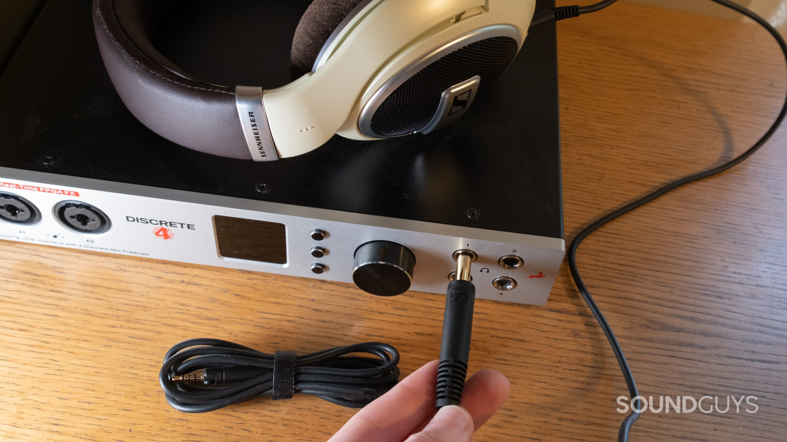 sennheiser-hd-599-plug-in The Sennheiser HD 599 rests on top of an audio interface with the 1/4-inch cable held in a hand inserting it into the headphone output. A wrapped 3.5mm cable rests nearby.