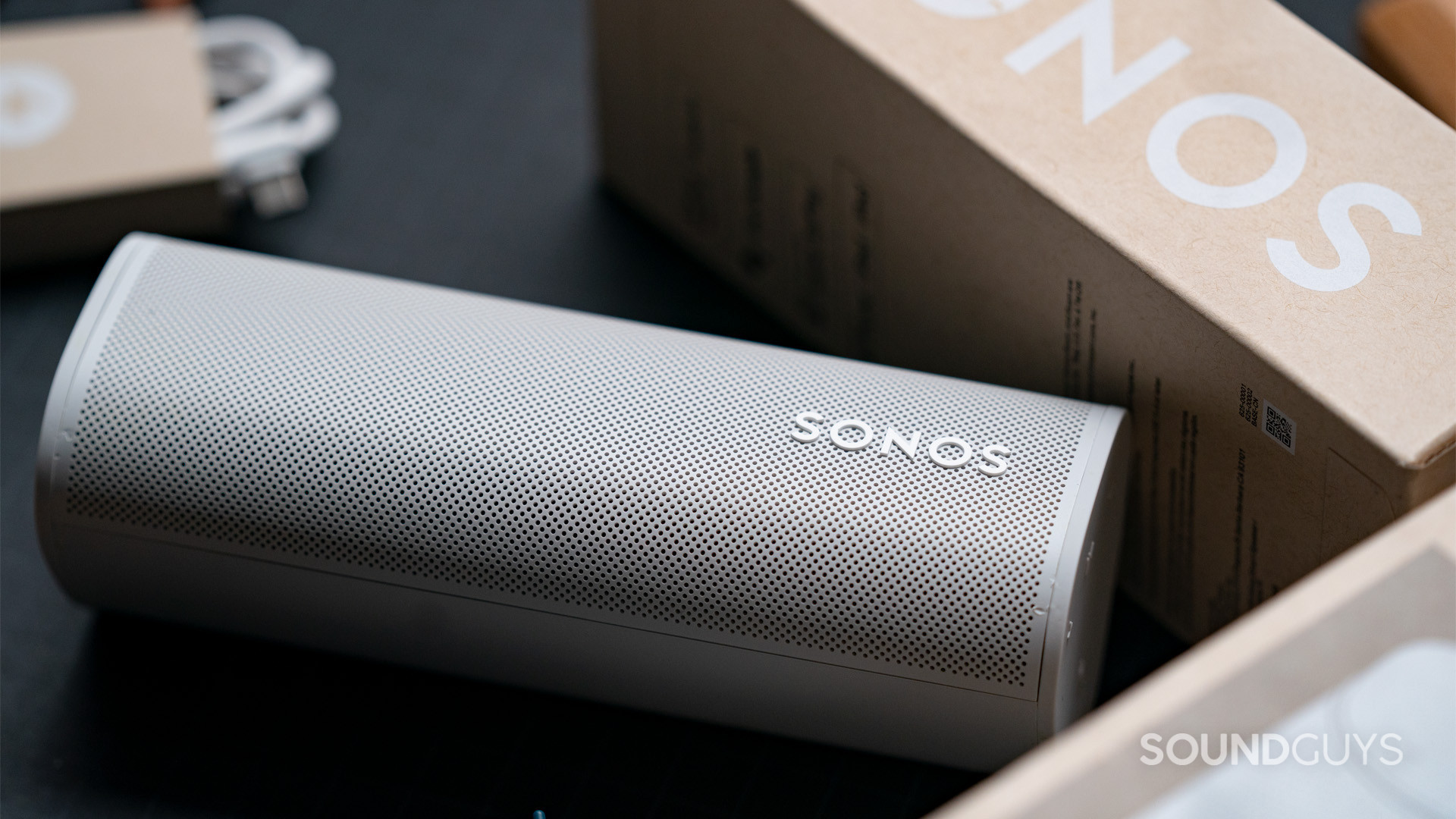 Sonos Roam Bluetooth smart speaker box(1) A Sonos Roam speaker sitting face-up next to the box it came in.