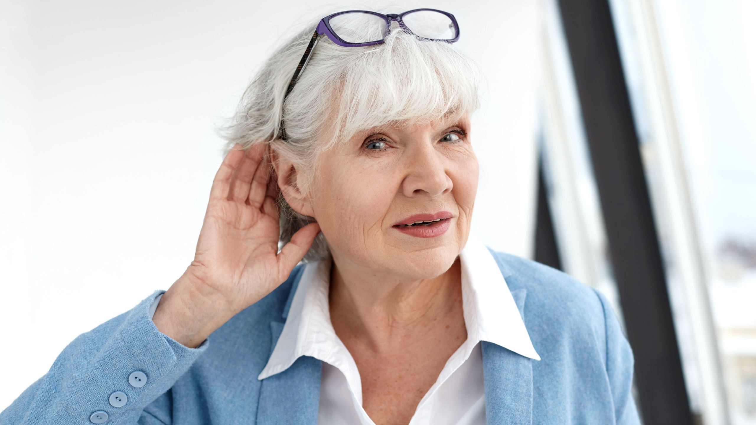 Woman Trying to Hear Better Elderly woman putting a hand behind her ear to hear better.